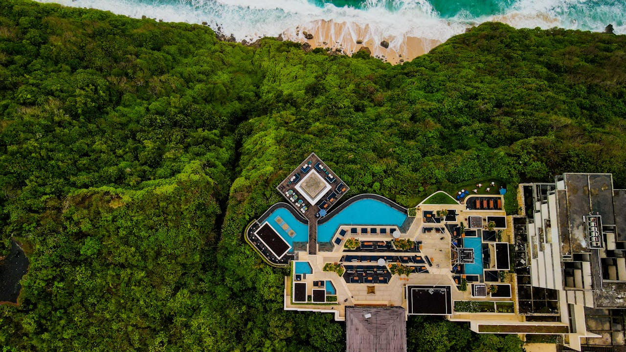 Stunning aerial shot of a luxury resort in Bali, surrounded by lush greenery and ocean view.
