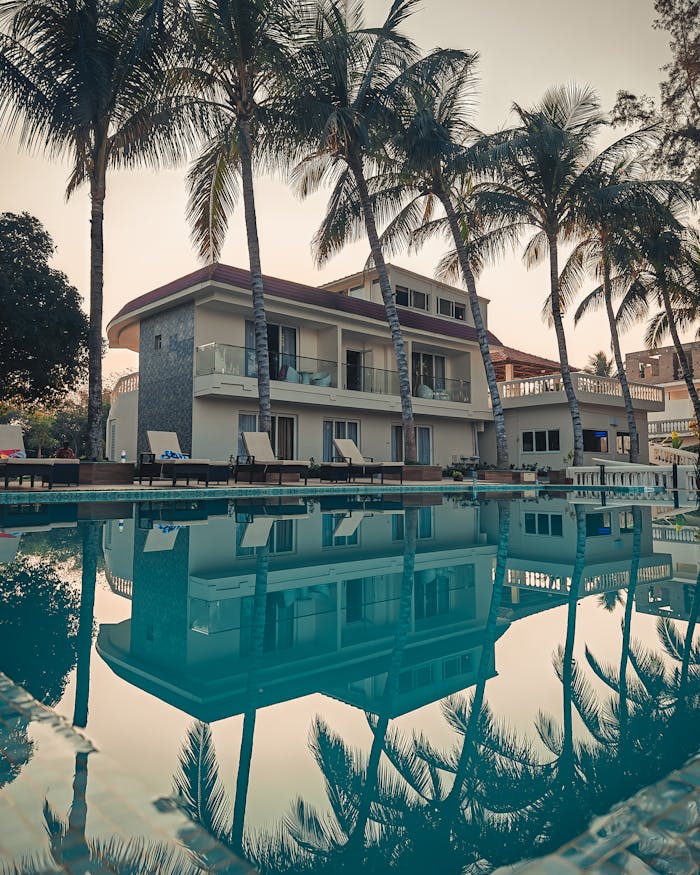 Serene resort setting with palm trees and pool reflection in Garchumbak, India.
